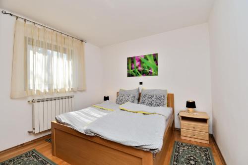 a white bedroom with a bed and a window at Apartment Tadey in Fužine