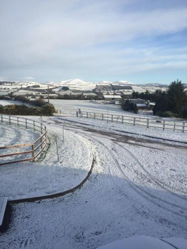 a snow covered road with a fence in the distance at Hunthill in Tulach an Iarainn