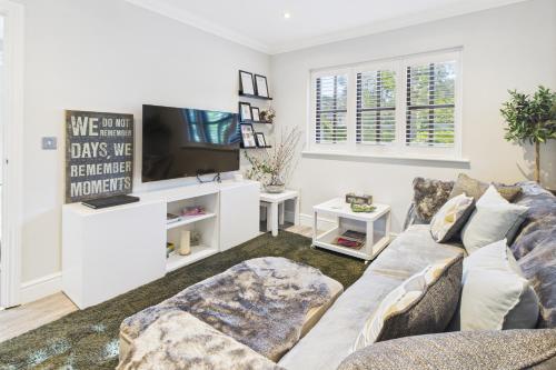 a living room with a couch and a tv at King size room with own bathroom & livingroom in a luxury home, free WiFi, HOMESTAY in West Byfleet