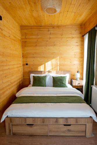 a bed in a room with a wooden wall at Natural cottage in Saguramo