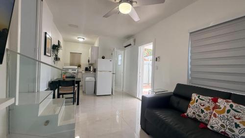 a living room with a black couch and a kitchen at Comfortable modern apartment- central location. in Miami