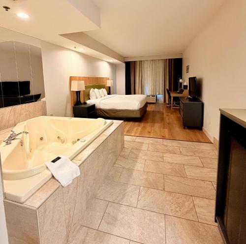 a hotel room with a tub and a bedroom at Radiant Inn and Suites in Murfreesboro