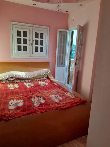 a bedroom with a bed with a red comforter at El Basha Apartment sea View in Dumyāţ al Jadīdah