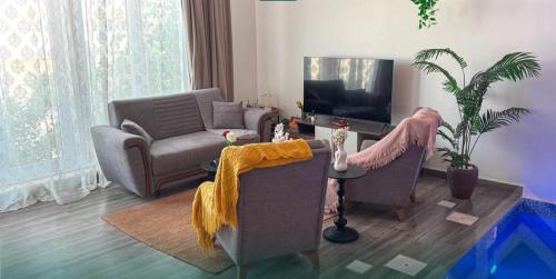 a living room with two chairs and a television at شاليه روجا Roja Chalet in As Sulayf