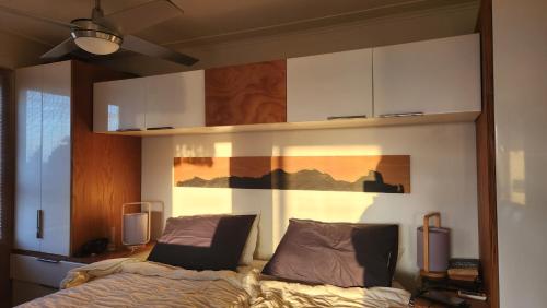 a bedroom with a bed and a wall with cabinets at Beachfront Sunset Bach in Piha
