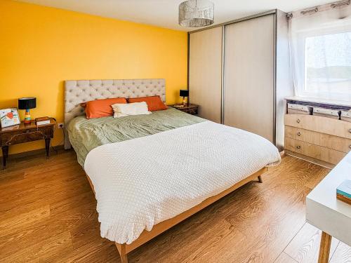 a bedroom with a bed and a yellow wall at Appartement lumineux proche Genève et Jura 3 chambres, terrasses et parking in Gex