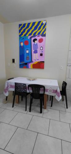 a table with two chairs and a painting on the wall at pousada Adriane in Rio do Sul
