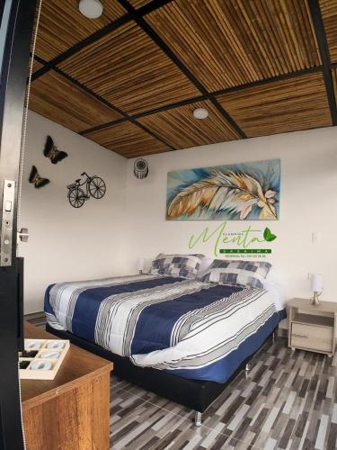 a bedroom with a bed with a painting on the wall at MeNTA GLAMPING in Sasaima