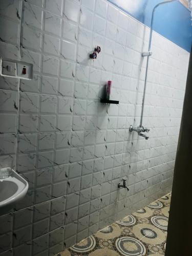 a bathroom with a white tiled shower with a sink at KFarm house in Kijabe