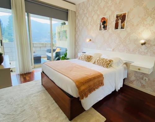 a bedroom with a large bed and a large window at Vale de Azereiros Apartamentos - Alojamento no Gerês in Geres