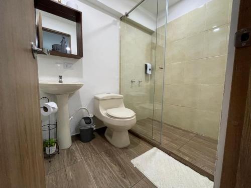 a bathroom with a toilet and a glass shower at Olivo House Casa Hotel in Envigado
