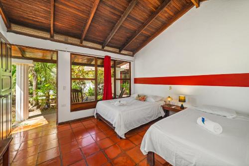 a bedroom with two beds and a large window at Hotel Hibiscus in Playa Junquillal