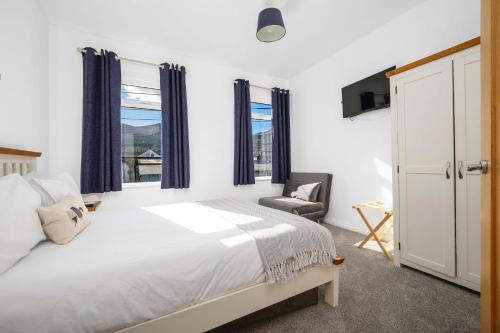 a bedroom with a bed and a chair and windows at Mournes Hot Tub Retreat, 4-Star Accommodation in Newcastle