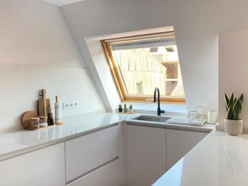 a white kitchen with a sink and a window at Salitre - Boa Onda in Cee