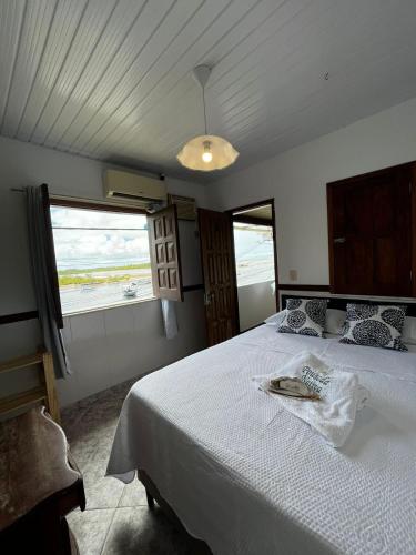 a bedroom with a large white bed with a view of the ocean at Pousada Nativa - Vista ao mar in Ilha de Boipeba