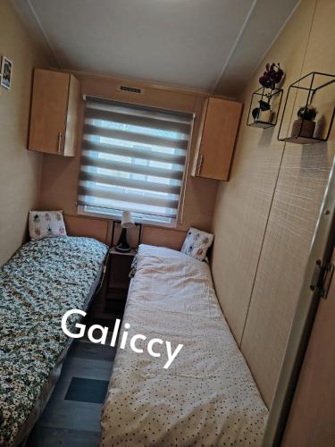a small room with two beds and a window at Caravan Galiccy in Kinmel Bay