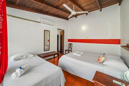 two beds in a room with white walls at Hotel Hibiscus Cabina 4 in Playa Junquillal
