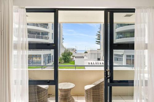 an open door to a balcony with a view of the ocean at Ocean Seascape - Mt Maunganui in Mount Maunganui