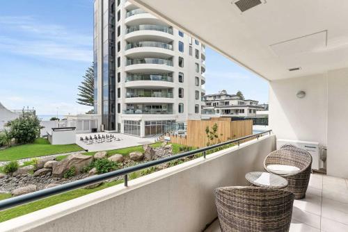 a balcony with two chairs and a building at Ocean Seascape - Mt Maunganui in Mount Maunganui