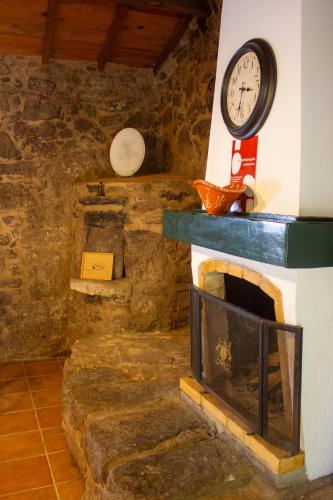 a room with a fireplace with a clock on the wall at Refugio dos Cartolas - Mountain Retreat in São Mamede