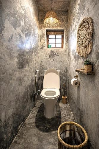 a bathroom with a toilet and a window and a chandelier at HA Beach Breeze in Jambiani