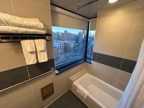 a bathroom with a bath tub and a window at Hotel Richland LES in New York