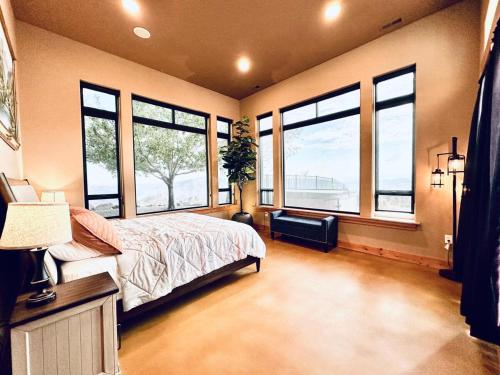 a bedroom with large windows and a bed and a table at Alpine Luxury Chelan Vacation Rentals in Chelan