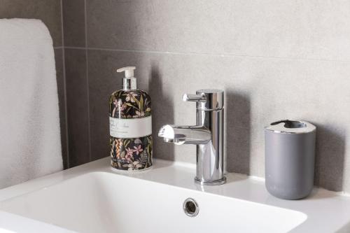 a bathroom sink with a bottle of soap on it at Mournes Hot Tub Retreat, 4-Star Accommodation in Newcastle