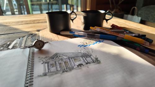 a drawing of a house on a table with pens at 瀬戸内の離島に泊まる一棟貸しコテージ unodo aoiouchi 焚き火, BBQ, キッチン 最大8名 in Mihara