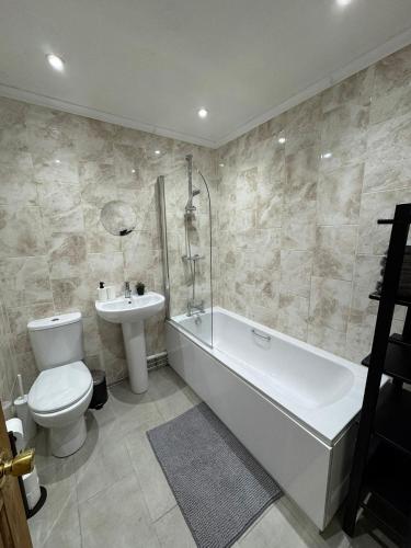 a bathroom with a tub and a toilet and a sink at Spacious Bournemouth Apartment in Bournemouth