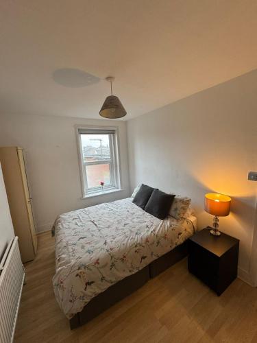 a bedroom with a bed with a lamp and a window at Spacious Bournemouth Apartment in Bournemouth