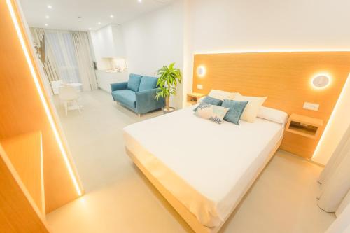 a bedroom with a large bed and a blue chair at Apartamentos Aires de Conil in Conil de la Frontera