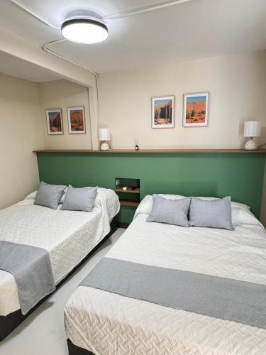 a room with two beds and a green wall at Suite 02 Montenegro Cerca de Consulado in Monterrey