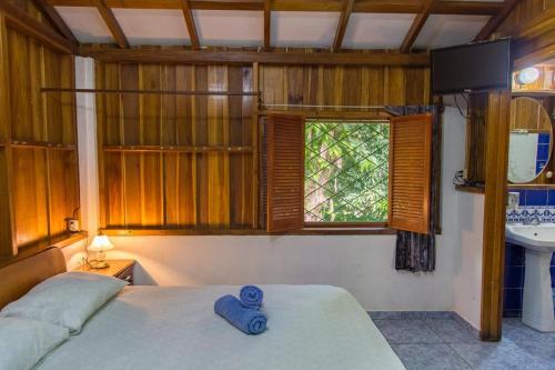 a bedroom with a bed and a sink and a window at Cabinas Iguana Cahuita in Cahuita