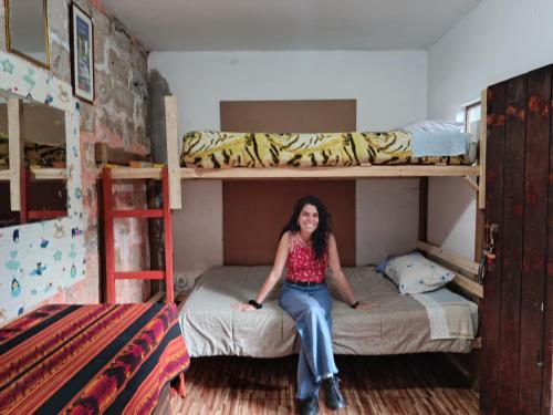 a woman sitting on a bed in a room with bunk beds at Hostel Viajeros Arequipa in Arequipa