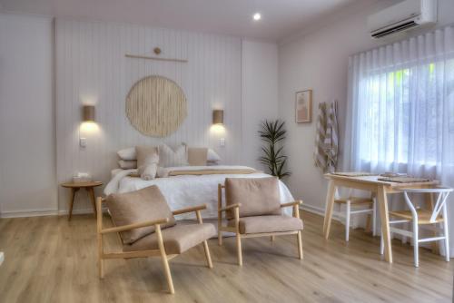 a bedroom with a bed and two chairs and a table at Solis in Agnes Water in Agnes Water