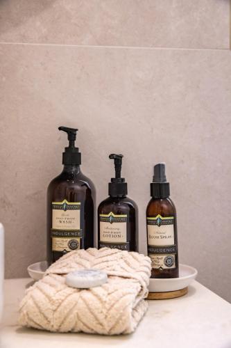 three bottles of soap on a counter with a towel at Solis in Agnes Water in Agnes Water