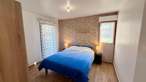 a bedroom with a blue bed and a window at Le Terrier in Noisiel