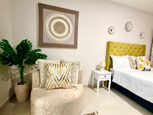 a bedroom with a bed and a chair and a plant at Orchid Belvedere Suites 102 - The Fig in Gaborone
