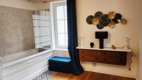 a bathroom with a tub and a window and a blue stool at Le Clos des Souvenirs in Étretat