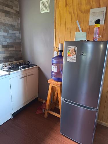 a kitchen with a stainless steel refrigerator and a stove at Tu Refugio Quellon in Quellón