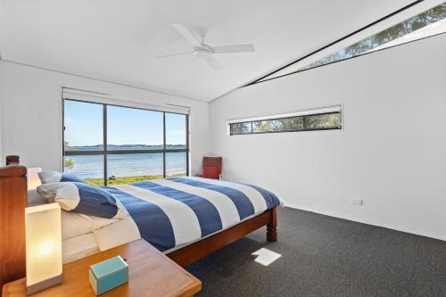 a bedroom with a bed and a large window at Pindimar Beach Sanctuary Absolute Beachfront in Pindimar