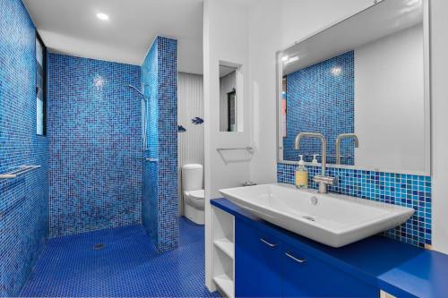 a blue and white bathroom with a sink and a shower at Pindimar Beach Sanctuary Absolute Beachfront in Pindimar