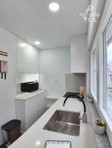 a white kitchen with a sink and a window at Refúgio da Vila in Vila de Rei