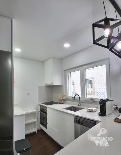 a white kitchen with a sink and a window at Refúgio da Vila in Vila de Rei