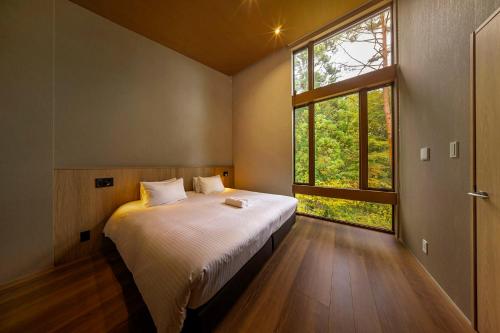 a bedroom with a bed and a large window at Chalet Infinity in Hakuba