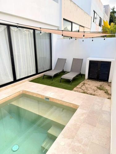 a patio with two chairs and a swimming pool at Cancún Arbolada Huayacan in Cancún