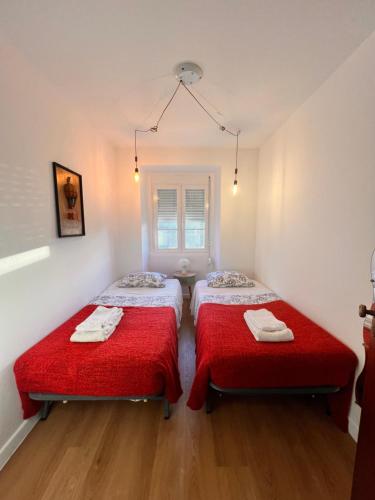 two beds in a small room with red sheets at Sintra Central Apartment in Sintra