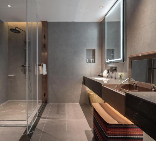 a bathroom with a glass shower and a sink at Jiuzhaigou A HOTEL in Jiuzhaigou