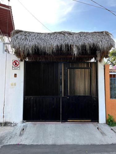 a black gate to a building with a thatched roof at Bungalows Teka in Zihuatanejo